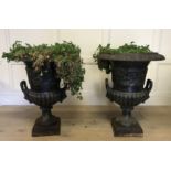A PAIR OF CAST IRON CLASSICAL CAMPAGNA URNS Applied with lion mask handles and embossed floral