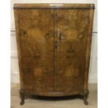 GOODALLS OF MANCHESTER, AN ART DECO WALNUT BOW FRONTED DWARF LINEN PRESS With carved decoration,