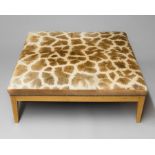 A TAXIDERMY GIRAFFE SKIN SOFA STOOL. (h 44cm x w 121cm x d 121cm)