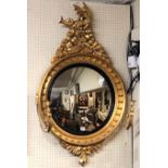 A REGENCY PERIOD GILT FRAMED CONVEX GIRONDELLE MIRROR Crested with a winged dragon above a