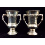 HAROLD STABLER, A PAIR OF EDWARDIAN SILVER VASES Having three handles and applied bands of Celtic