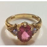 AN 18CT GOLD, TOURMALINE AND TANZANITE RING Having an oval cut pink tourmaline flanked by tanzanite,