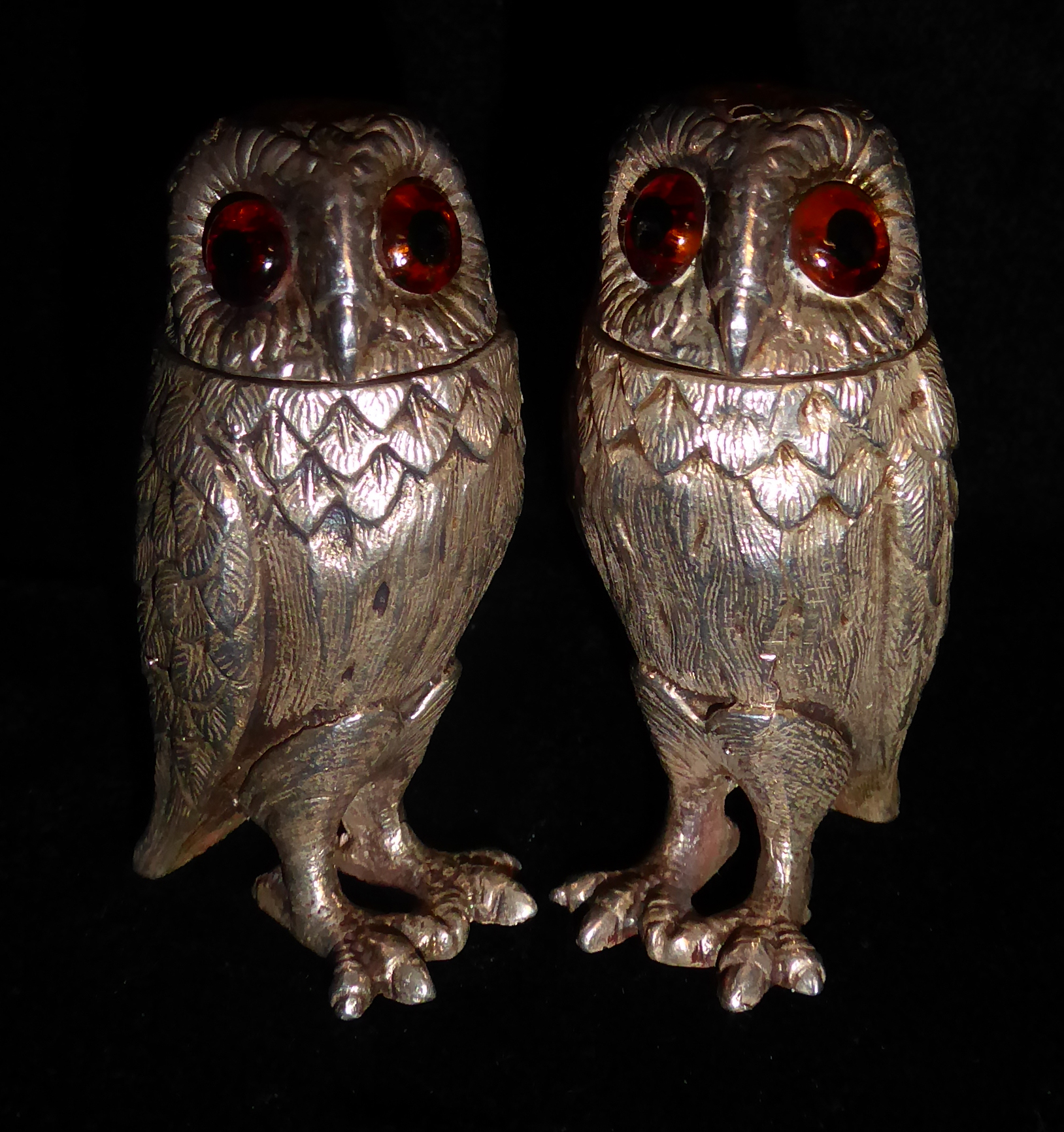 A PAIR OF NOVELTY SILVER OWL PEPPER POTS The detachable heads set with amber glass eyes and embossed