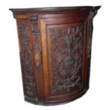 A 19TH CENTURY WALNUT AND MAHOGANY BOW FRONTED PANEL Heavily carved with armour weapons, foliage and