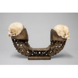 A PAIR OF LATE 19TH/EARLY 20TH CENTURY KORWAR TRIBE ANCESTOR HUMAN SKULLS ON A CARVED WOODEN