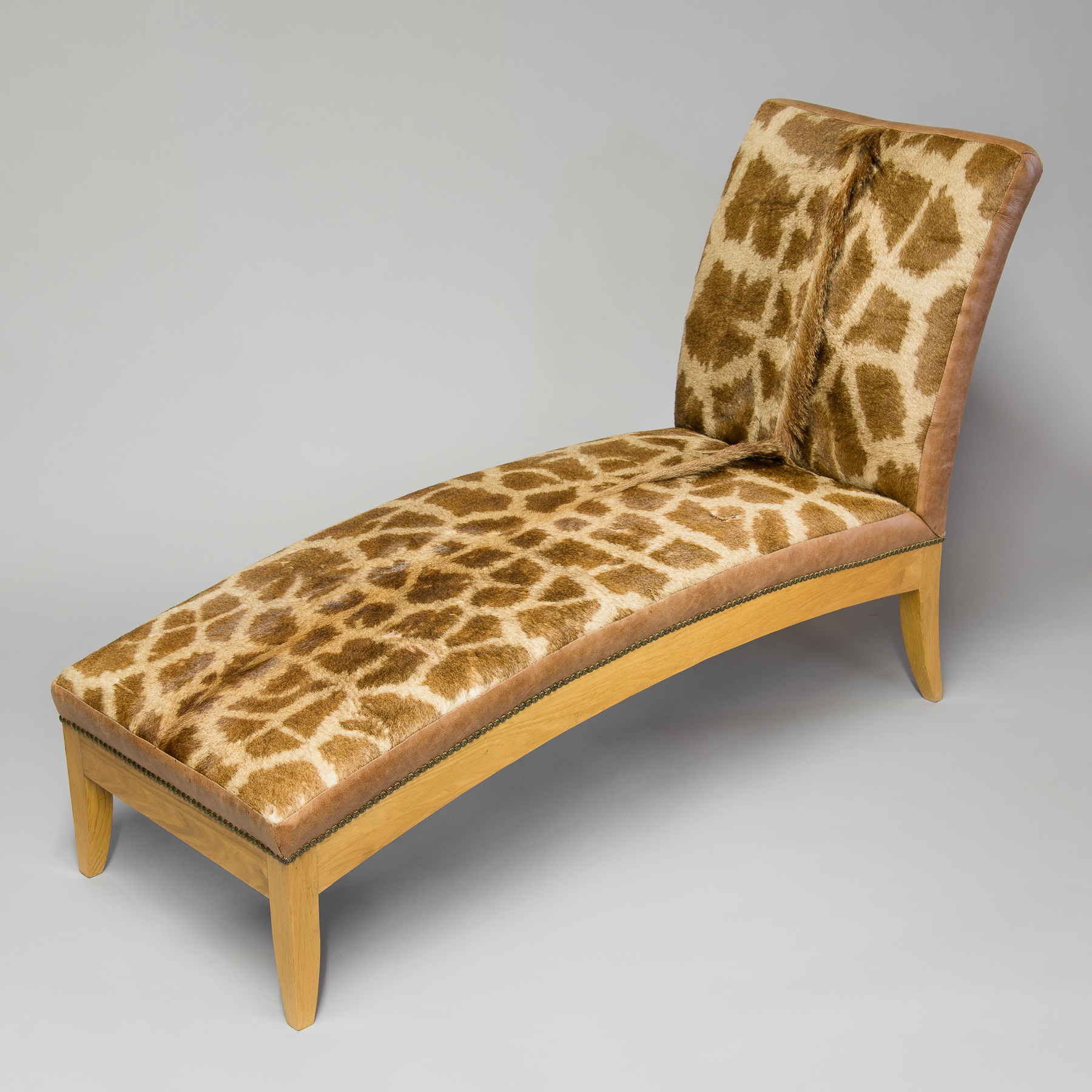 A TAXIDERMY GIRAFFE SKIN CHAISE. (h 92cm x w 55cm x d 154cm)