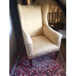 A GEORGE III MAHOGANY UPHOLSTERED WINGBACK ARMCHAIR Raised on square section reeded legs terminating