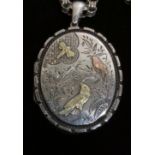 A VICTORIAN SILVER AESTHETIC DESIGN OVAL LOCKET AND CHAIN Engraved with exotic birds and having