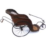 A VICTORIAN WICKER BATH CHAIR/INVALIDS CHAIR With iron framework and three spoked wheels.