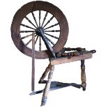 AN ANTIQUE OAK SPINNING WHEEL With turned spokes and hinged pedal.