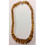 A VINTAGE 9CT GOLD AND AMBER NECKLACE The single strand of graduated square cut amber beads with a