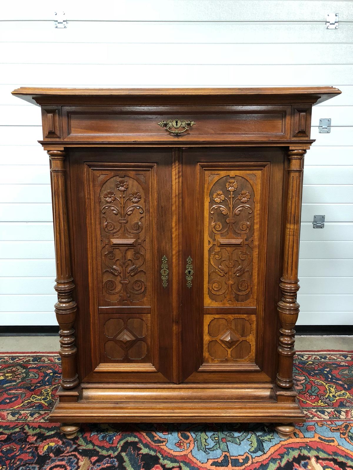 ANTIQUE STYLE WALNUT CUPBOARD WITH SINGLE DRAWER, WITH CARVED FLORAL SCROLL PATTERNS AND CARVED