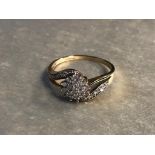 A 9CT GOLD AND DIAMOND CLUSTER RING HAVING A DAISY DESIGN IN THE MIDDLE WITH A DIAMOND CURVE