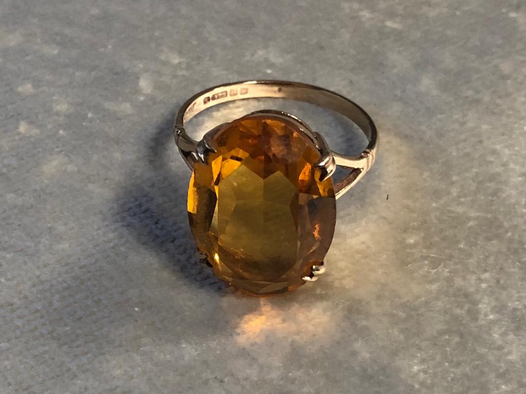 A 9CT GOLD AND CITRINE DRESS RING HAVING A LARGE OVAL SHAPE CITRINE HELD WITH FOUR PRONGS SIZE P