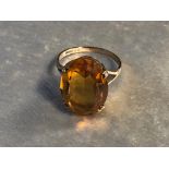 A 9CT GOLD AND CITRINE DRESS RING HAVING A LARGE OVAL SHAPE CITRINE HELD WITH FOUR PRONGS SIZE P