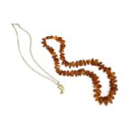 A gold Egyptian head pendant, on a 9ct gold curb link chain, and a single row free form amber bead