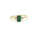 An emerald and diamond three stone ring, with an emerald cut emerald four claw set to the centre,