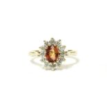 A 9ct gold orange sapphire and diamond cluster ring, mixed cut orange sapphire, claw set to twelve