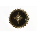 A Victorian split pearl and black onyx circular brooch, a split pearl star raised boss on a black