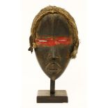 A Dan mask,20th century, Ivory Coast, wooden with shut eyes and vertical ridge to the forehead, a