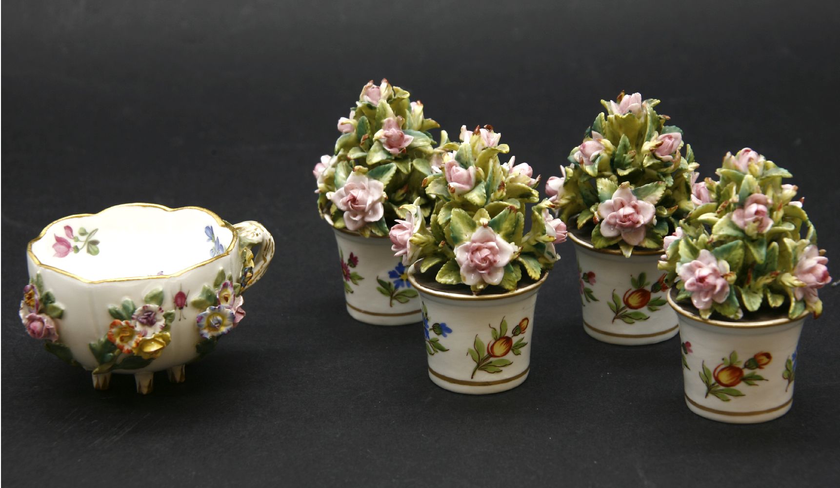 A Meissen cup, floral encrusted, and four Continental flowers in pots