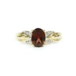 A gold single oval cut garnet ring with diamond set shoulders, marked 585 and 14k,3.41g