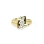An 18ct gold three stone portrait brilliant cut diamond ring, with open textured shoulder and a