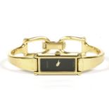 A ladies gold plated Gucci quartz bangle watch, black dial, signed Gucci, with a tapering stiff