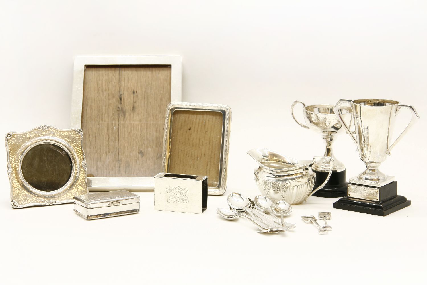 Silver items, to include three frames, two trophies, a jug, a matchbox holder, and coffee spoons