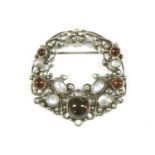 An Art Nouveau style silver garnet and moonstone cabochon openwork brooch