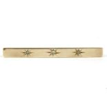 A gold three stone star set diamond bar brooch, (tested as approximately 9ct gold),3.90g