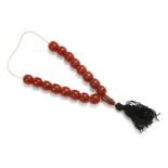 A partial single row uniformed cherry coloured Bakelite prayer bead necklace, with black silk tassel