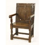 An oak wainscot armchair,with a carved frame, two linen fold panels over a solid seat, turned