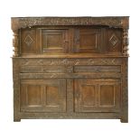 An oak court cupboard, 17th century, carved with scrolling vines, the frieze over two cupboard doors