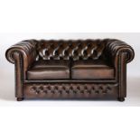 A pair of modern brown leather two-seat chesterfield settees,with deep buttoned upholstery, seat