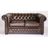 A modern brown leather two-seat chesterfield settee,with deep buttoned upholstery, seat cushions and