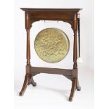 A Victorian oak dinner gong,on a turned stand and outswept supports,65cm wide91cm high