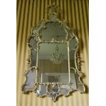 A George II giltwood wall mirror,c.1755, the shallow bevelled oblong plate within a scrolled