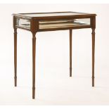 A reproduction mahogany bijouterie table,the glazed, hinged top on turned and fluted legs,71cm