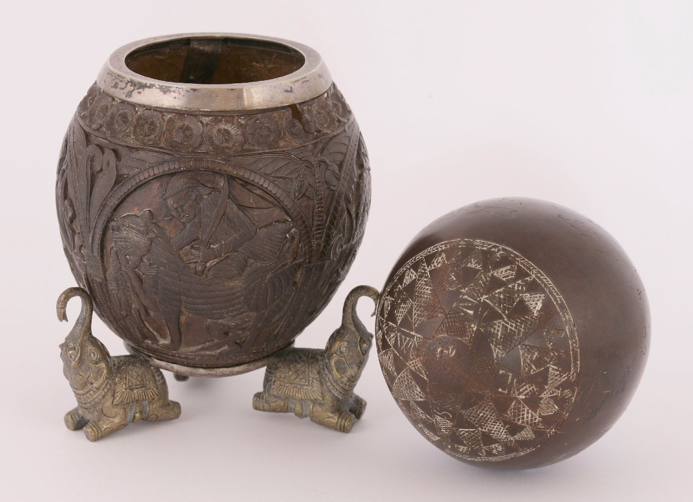 An Indian carved coconut shell,19th century, worked with figural panels below a flower head border