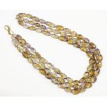 A three row graduated oval faceted ametrine bead necklace, strung knotted to a gilt metal hook