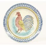 A tin glazed plate, painted with a cockerel within a sponged blue and yellow border. 32cm diam.