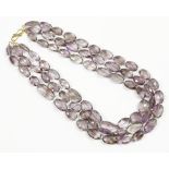 A three row graduated oval faceted amethyst bead necklace, strung knotted to a gilt metal hook