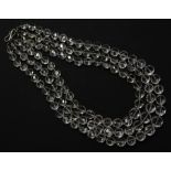 A three row graduated faceted bouton shaped rock crystal bead necklace, strung knotted to a silver