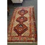 A triple banded red and cream border rug, cream ground with red and blue hexagonal design, densely