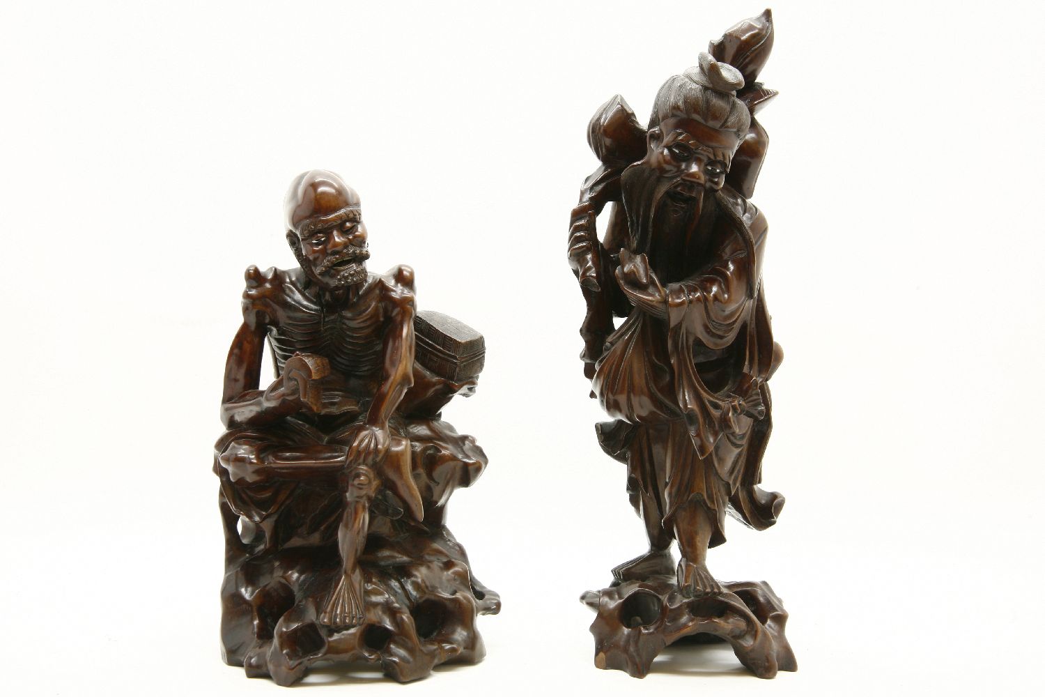 Two Chinese carved hardwood figures: one skeletal, seated, holding a book, the other holding a