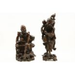 Two Chinese carved hardwood figures: one skeletal, seated, holding a book, the other holding a