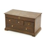 An oak chest,19th century, the hinged top over an arrangement of five drawers, with ivory bun