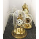 Four brass 40 day clocks, 3 with glass domes and 5 further glass domes. Tallest 32cm high