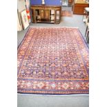 A multiple banded blue and red border rug, with densely populated blue ground, with green, cream and
